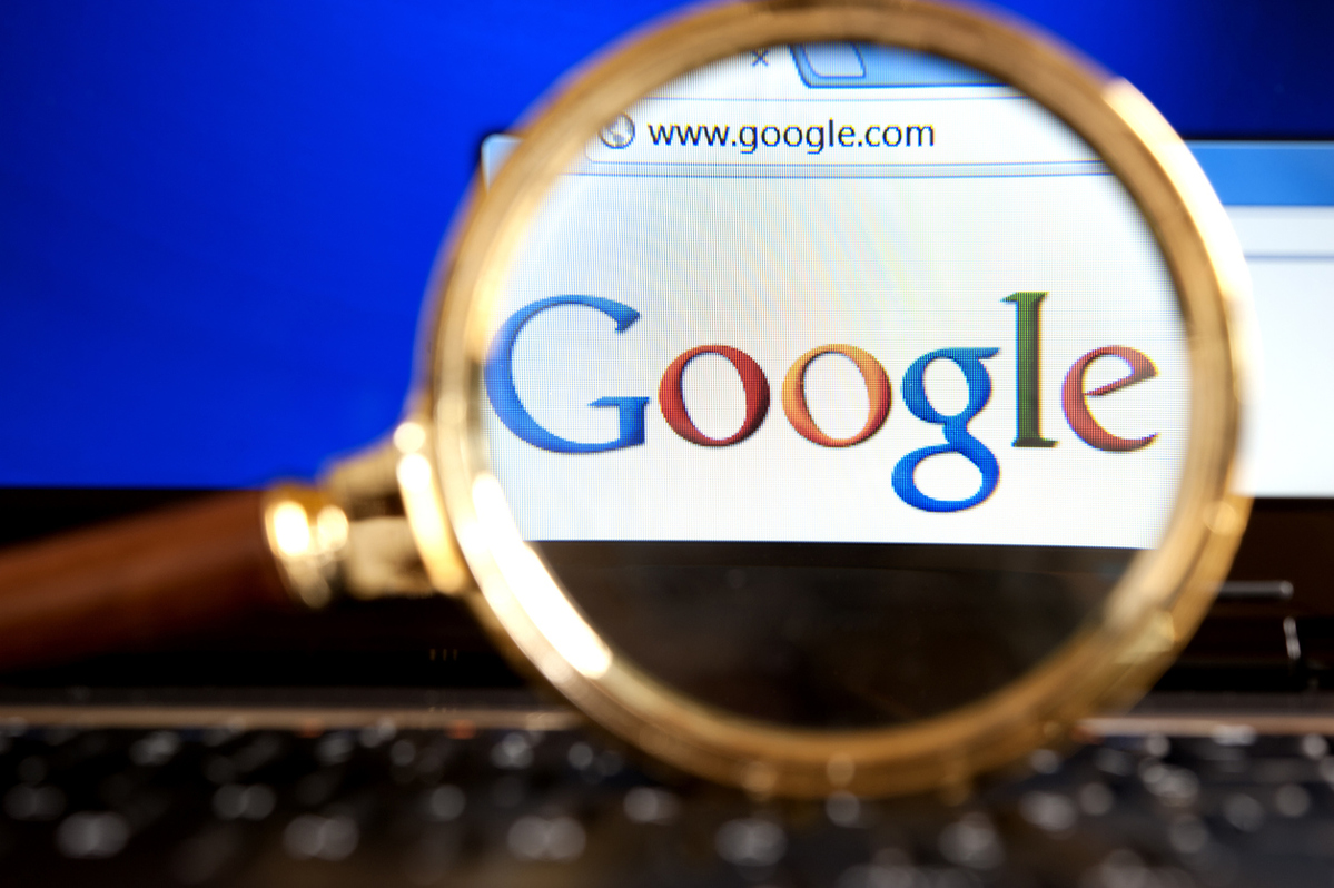 Google website through a magnifying glass|Google company sign with street address
