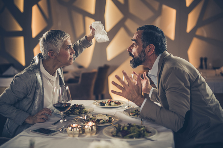 Frustrated mature couple arguing on a dinner in a restaurant.