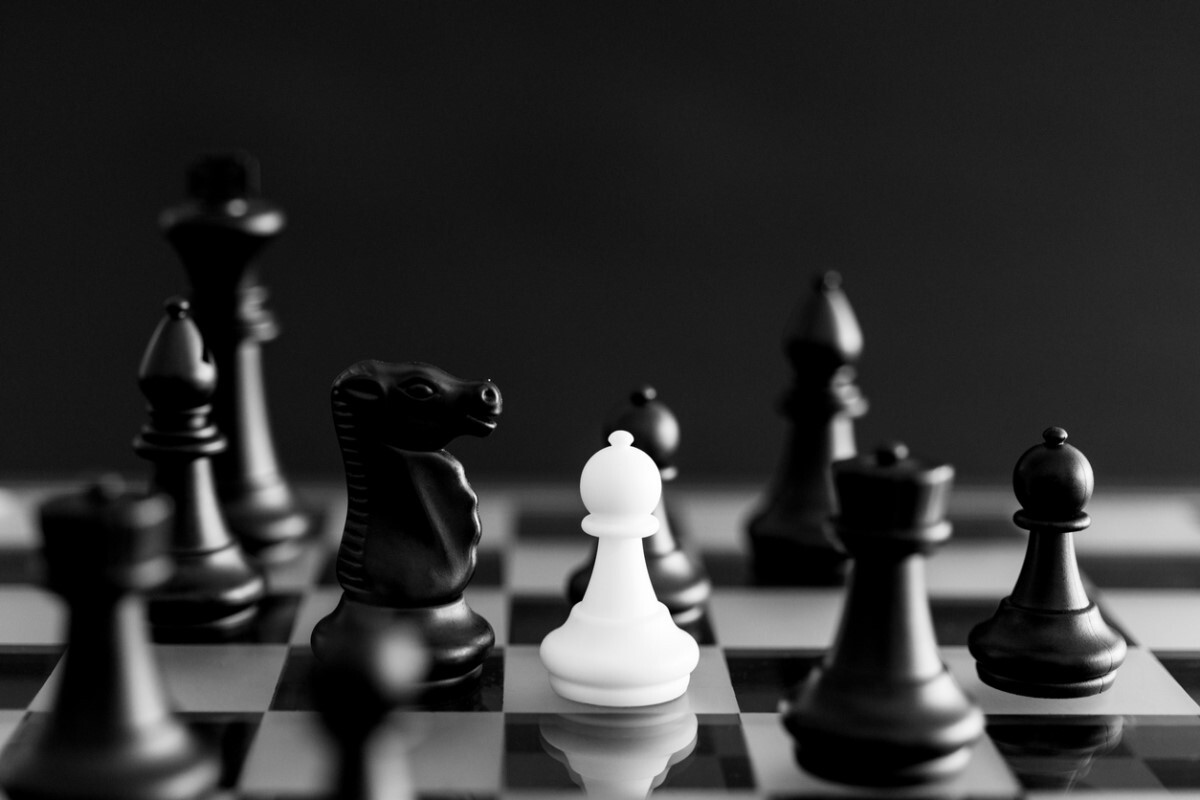 White pawn and black chess pieces on chessboard